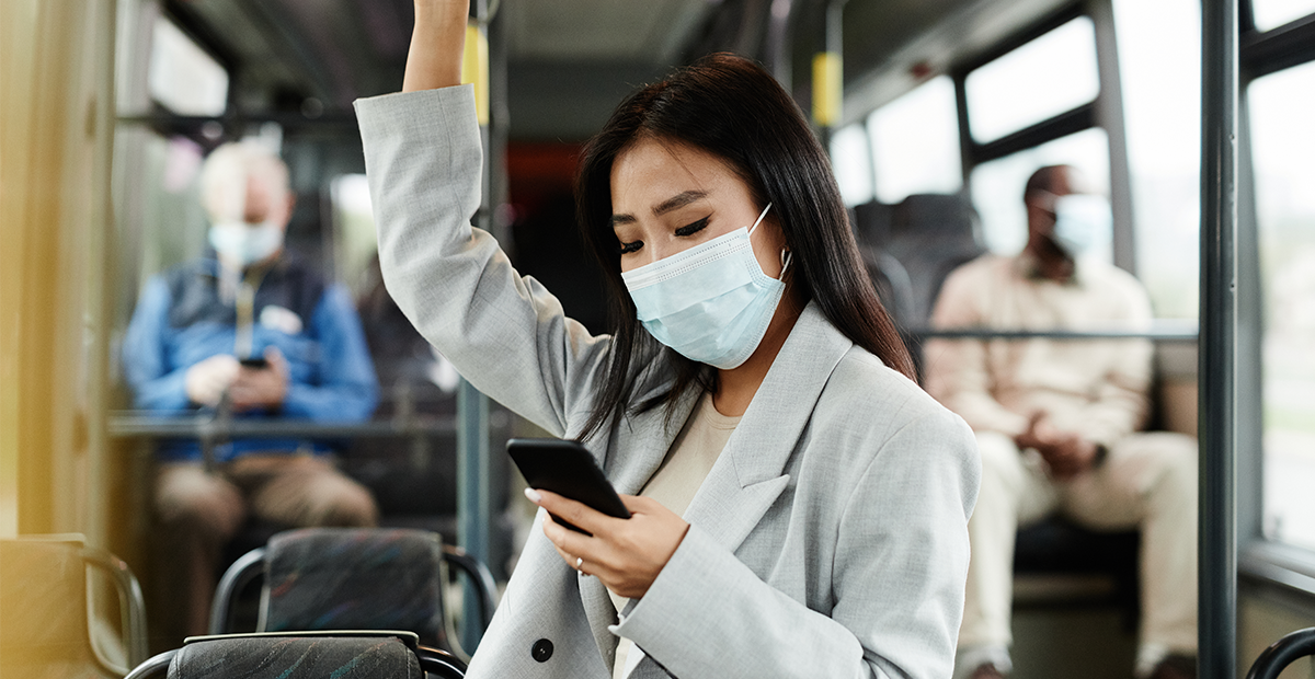 Woman wearing mask riding public bus.